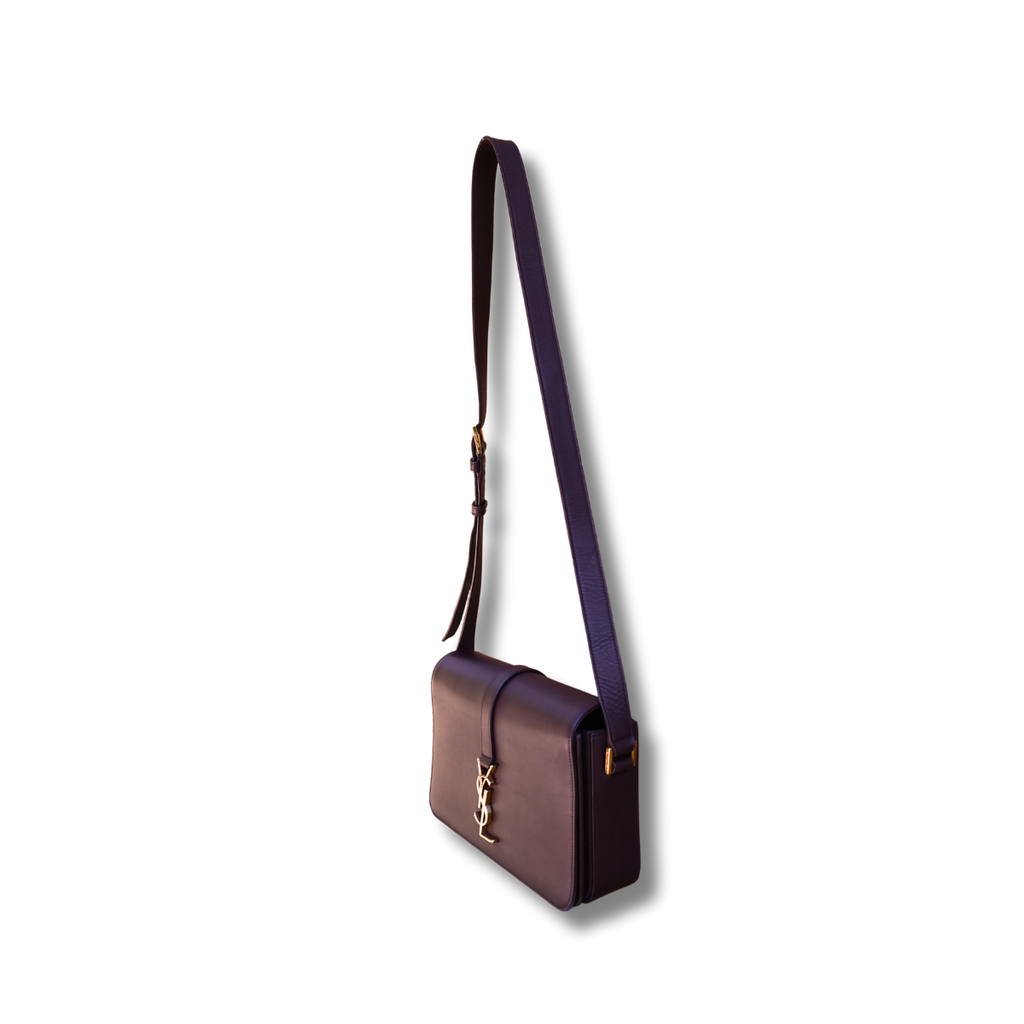 A burgundy Saint Laurent satchel crossbody bag with a gold-finish logo, displayed against a white background