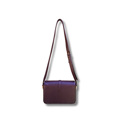 A burgundy Saint Laurent satchel crossbody bag with a gold-finish logo, displayed against a white background
