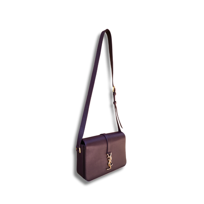A burgundy Saint Laurent satchel crossbody bag with a gold-finish logo, displayed against a white background