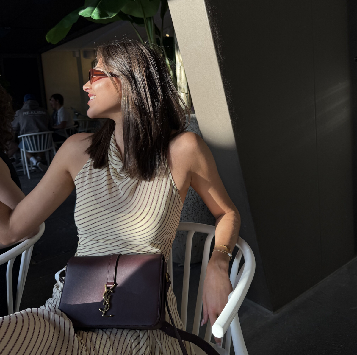 A burgundy Saint Laurent satchel crossbody bag with a gold-finish logo, displayed against a white background.