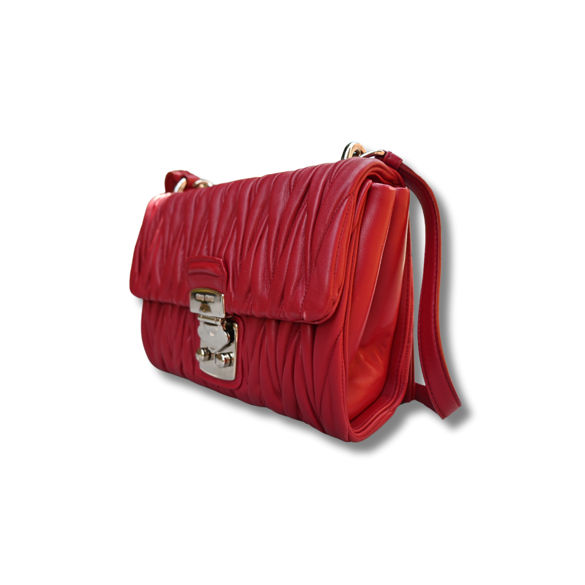 A red Miu Miu matelassé nappa leather shoulder bag with a textured finish, featuring a logo on the front and a chain strap.