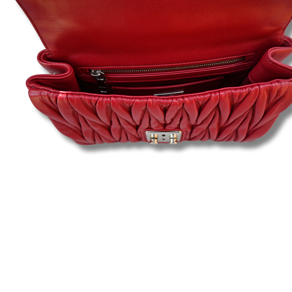 A red Miu Miu matelassé nappa leather shoulder bag with a textured finish, featuring a logo on the front and a chain strap.